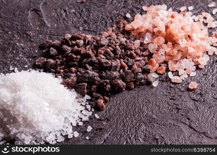 Various tupes of salts, pink Himalayas and black with sea salt on slate background. Various tupes of salts