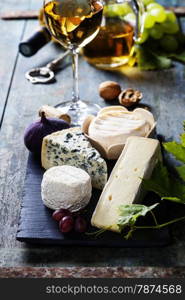 Various types of cheese and white wine on wooden background