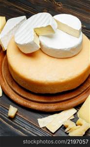 Various types of cheese - parmesan, brie, roquefort, cheddar on wooden background or table. Various types of cheese - parmesan, brie, roquefort, cheddar