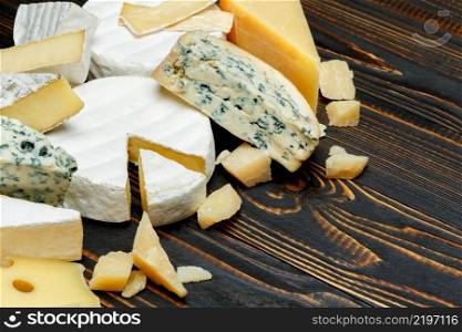 Various types of cheese - parmesan, brie, roquefort, cheddar on wooden background or table. Various types of cheese - parmesan, brie, roquefort, cheddar
