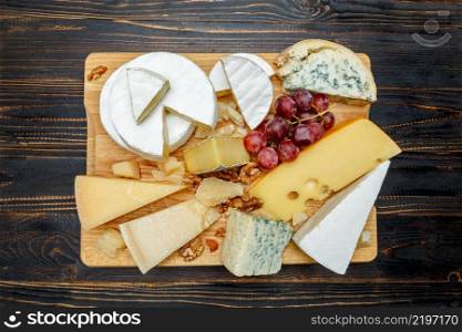 Various types of cheese - parmesan, brie, roquefort, cheddar on wooden cutting board. Various types of cheese - parmesan, brie, roquefort, cheddar