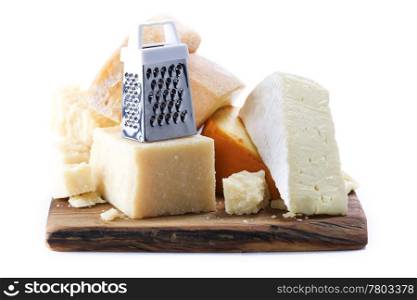 Various types of cheese with grater on wooden board