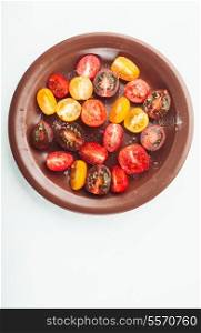 Various types of cherry tomatoes on the plate, isolated on white