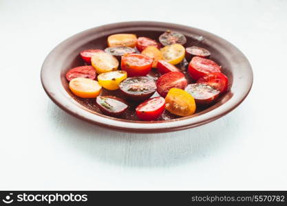 Various types of cherry tomatoes on the plate, isolated on white