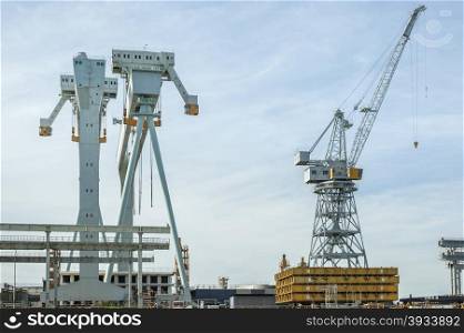 Various types of cranes at work in a shipyard