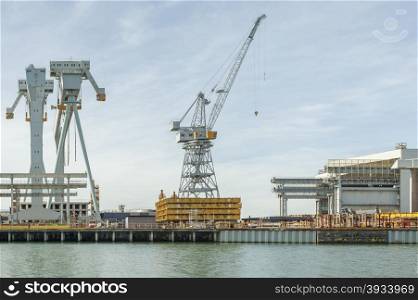 Various types of cranes at work in a shipyard