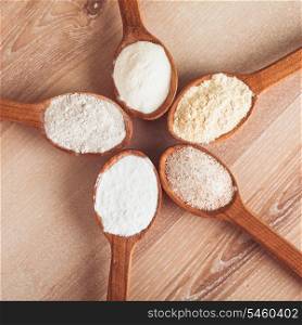 Various types of flour in five wooden spoons