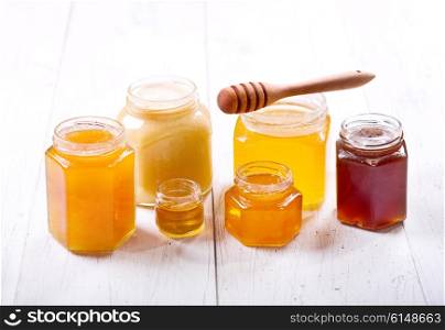 various types of honey in glass jars on a wooden table