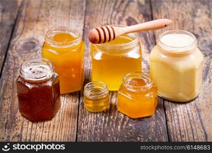 various types of honey in glass jars on a wooden table