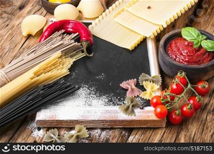 Various types of Italian pasta on rustic background. Raw pasta and lasagna