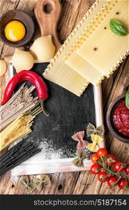 Various types of Italian pasta on rustic background. Raw pasta and lasagna