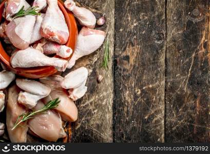 Various types of raw chicken meat with herbs in a bowl. On wooden background.. Various types of raw chicken meat with herbs in a bowl.