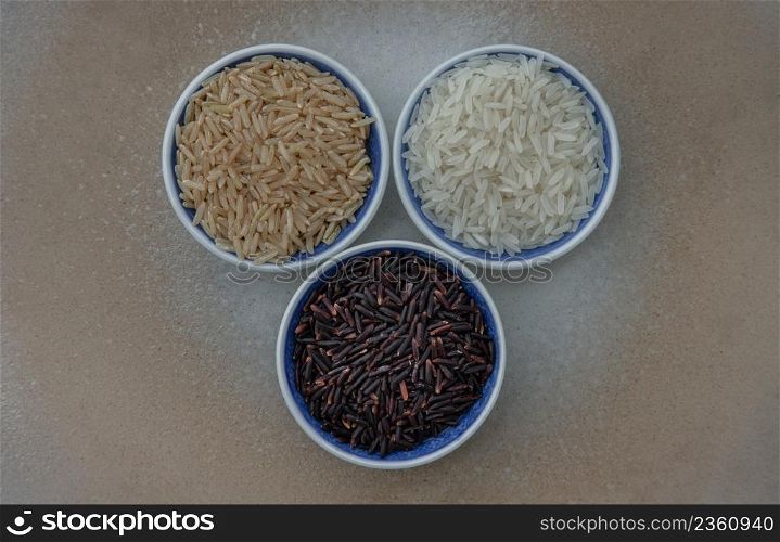 Various types of rice : Brown rice, Jasmine rice, Riceberry ceramic cup. Organic raw rice collection, Healthy food and diet concept, Overhead view, Selective focus.