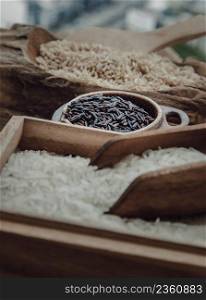 Various types of rice : Brown rice, Jasmine rice, Riceberry on old wooden background. Organic raw rice collection, Healthy food and diet concept, Selective focus.