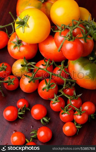 Various types of tomatoes on wooden background