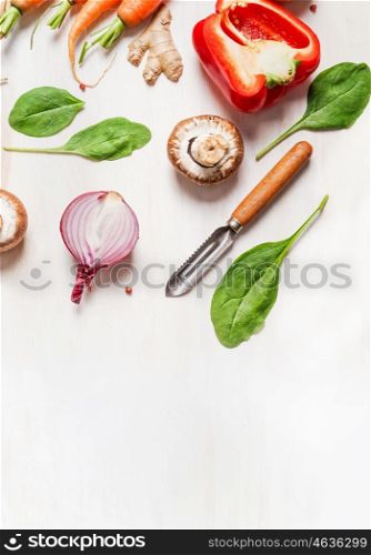 various vegetables ingredients for salad or healthy cooking with peeler on white wooden background, top view