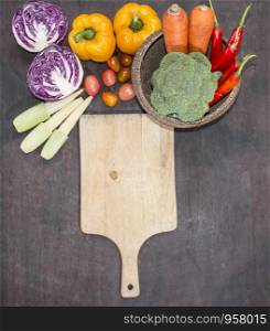 Various vegetables with cutting board on wooden background,top view