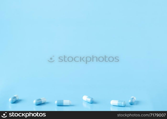 Various white-blue medication capsules. Blue background with copy space. Various white-blue medication capsules. Blue background with text space