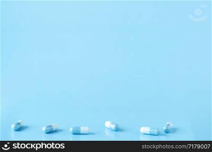 Various white-blue medication capsules. Blue background with copy space. Various white-blue medication capsules. Blue background with text space