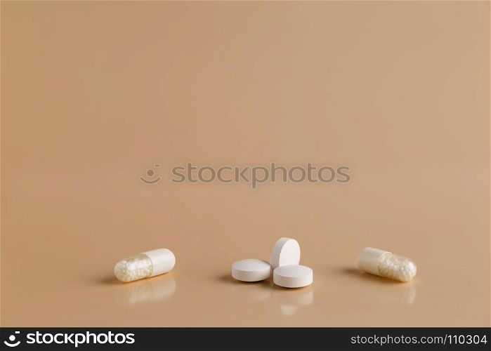 Various white pills and capsules. Various white pills on beige background
