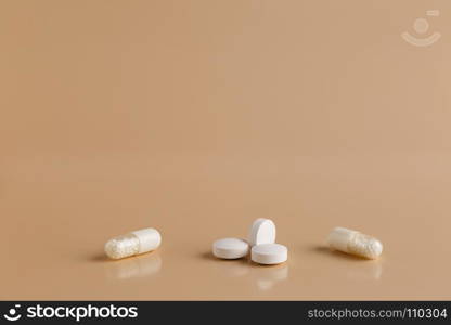 Various white pills and capsules. Various white pills on beige background