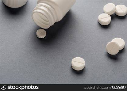 Various white plastic pill bottles and heap of drugs. Various white plastic pill bottles and heap of drugs on grey background