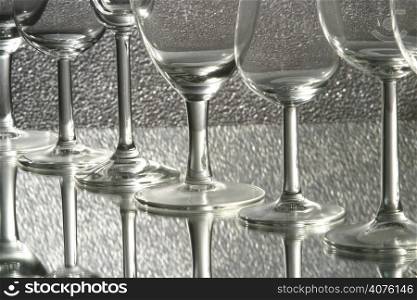 Various wine glasses standing on a reflective surface.