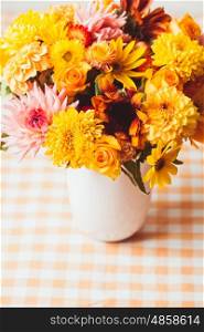 Vase with flowers on the table in a kitchen. Autumn yeloow flowers