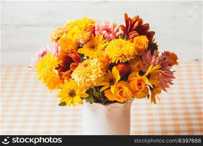 Vase with flowers on the table in a kitchen. Autumn yeloow flowers