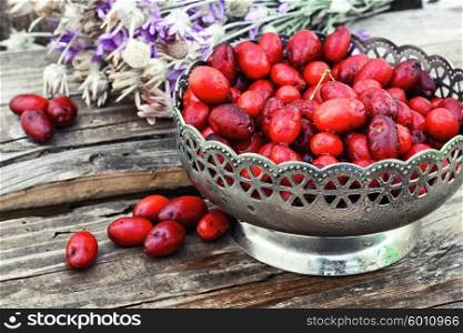 Vase with ripe cornelian cherry. Harvest ripe berries of dogwood in stylish vase