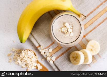Vegan banana and oatmeal smoothie in a glass on white marble background. Healthy food concept.