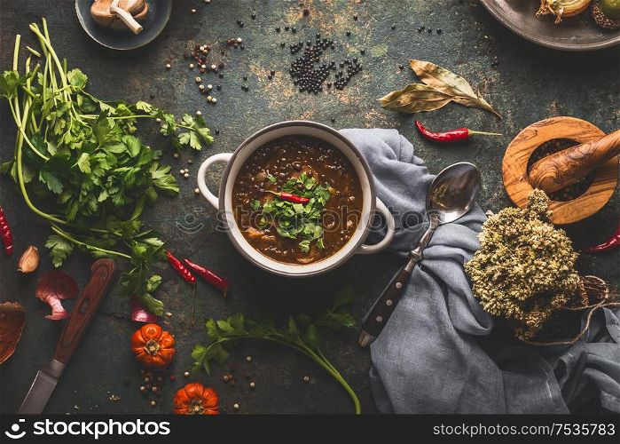 Vegan food. Bowl with lentil soup on rustic kitchen table background with various ingredients. Top view