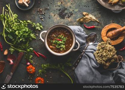 Vegan food. Bowl with lentil soup on rustic kitchen table background with various ingredients. Top view