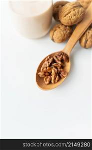 Vegan milk from nuts in a glass cup with various nuts on a white table, nuts in a wooden spoon. Vegan milk from nuts in a glass cup with various nuts on a white table, nuts in a wooden spoon.