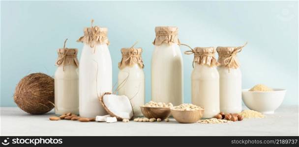 Vegan non dairy plant based milk in bottles and ingredients on blue background. Alternative lactose free milk substitute