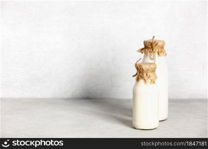 Vegan non dairy plant based milk in bottles on light background. Alternative lactose free milk substitute, copy space