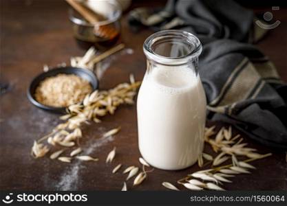 Vegan oat milk in glass bottle and ingredients for cooking. Healthy vegetarian non-dairy drink or beverage. Alternative milk
