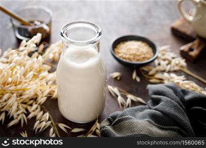 Vegan oat milk in glass bottle and ingredients for cooking. Healthy vegetarian non-dairy drink or beverage. Alternative milk
