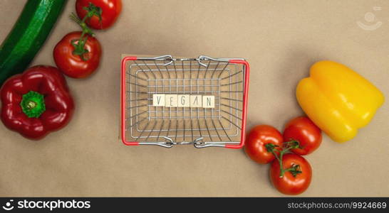 Vegan written on wooden cubes surrounded with vegetables in shoppin basket top view with craft paper background, Vegan, Healthy food, Vegetarian concept, copy space lifestyle. Vegan written on wooden cubes surrounded with vegetables in shoppin basket top view with craft paper background, Vegan, Healthy food, Vegetarian concept, copy space