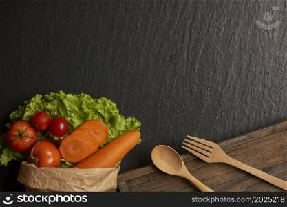 vegetable concept a paper bag of various vegetables such as carrots, tomatoes, and lettuce being placed on dark background.
