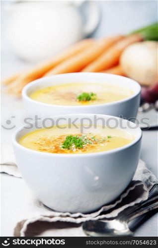 Vegetable cream soup in bowl over grey concrete background, copy space, vertical composition