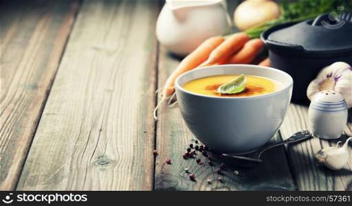 Vegetable cream soup in bowl over old wooden background, copy space
