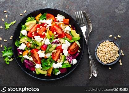 Vegetable dish, salad with avocado, pepper, tomato, italian mix, fresh lettuce, feta cheese and pine nuts. Healthy food. Top view