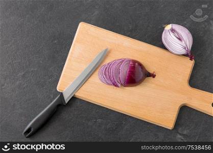 vegetable, food and culinary concept - chopped red onion and kitchen knife on wooden cutting board. red onion and kitchen knife on cutting board