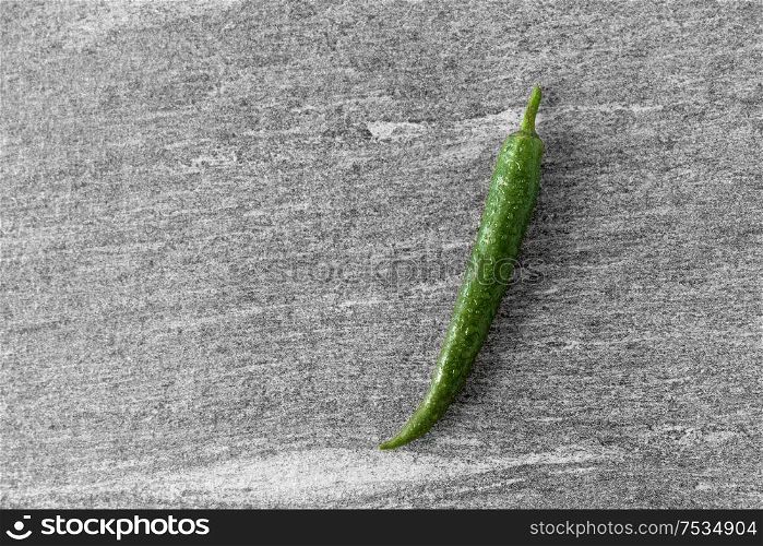 vegetable, food and culinary concept - close up of green chili pepper on slate stone background. green chili pepper on slate stone background