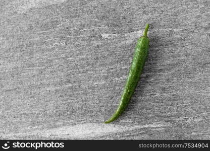 vegetable, food and culinary concept - close up of green chili pepper on slate stone background. green chili pepper on slate stone background