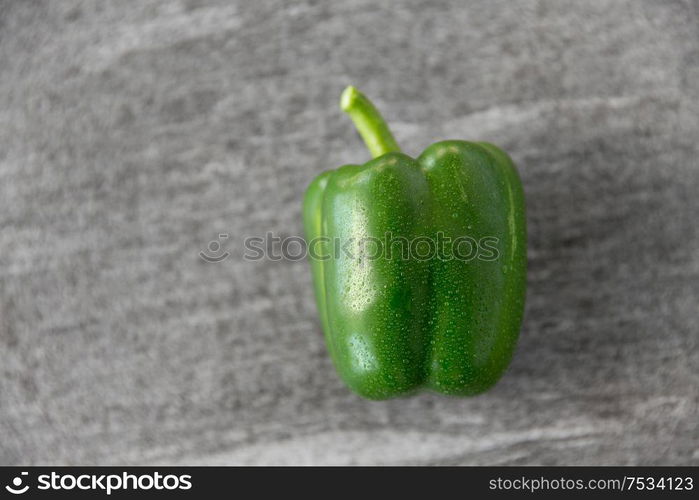 vegetable, food and culinary concept - close up of green pepper on slate stone background. close up of green pepper on slate stone background