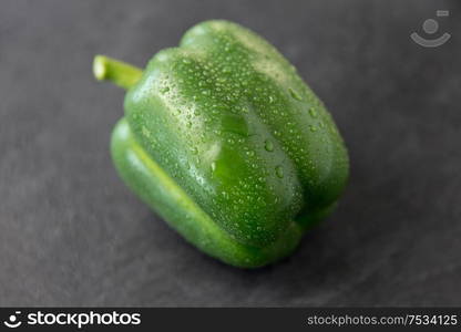 vegetable, food and culinary concept - close up of green pepper on slate stone background. close up of green pepper on slate stone background