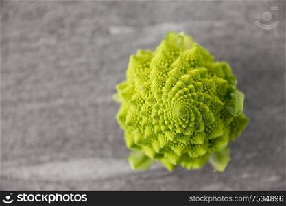 vegetable, food and culinary concept - close up of romanesco broccoli on slate stone background. close up of romanesco broccoli on slate stone