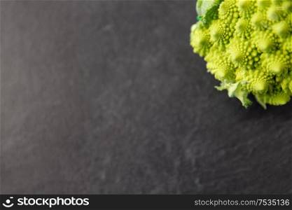 vegetable, food and culinary concept - close up of romanesco broccoli on slate stone background. close up of romanesco broccoli on slate stone